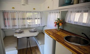 Una kitchenette compacta con una mesita, un lavamanos y un refrigerador.