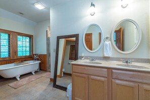 Ein Badezimmer mit einer freistehenden Badewanne, zwei Waschbecken, Holzschränken und einem großen Spiegel.