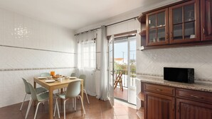 Une cuisine moderne avec un coin repas, comprenant une table en bois, des chaises et un four à micro-ondes.