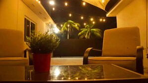 Une pièce avec deux chaises blanches, une table en verre et une plante en pot rouge.