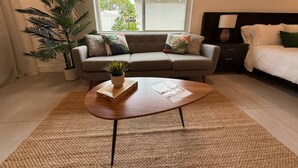 Un salon avec un canapé, une table basse, une plante en pot et un lit.