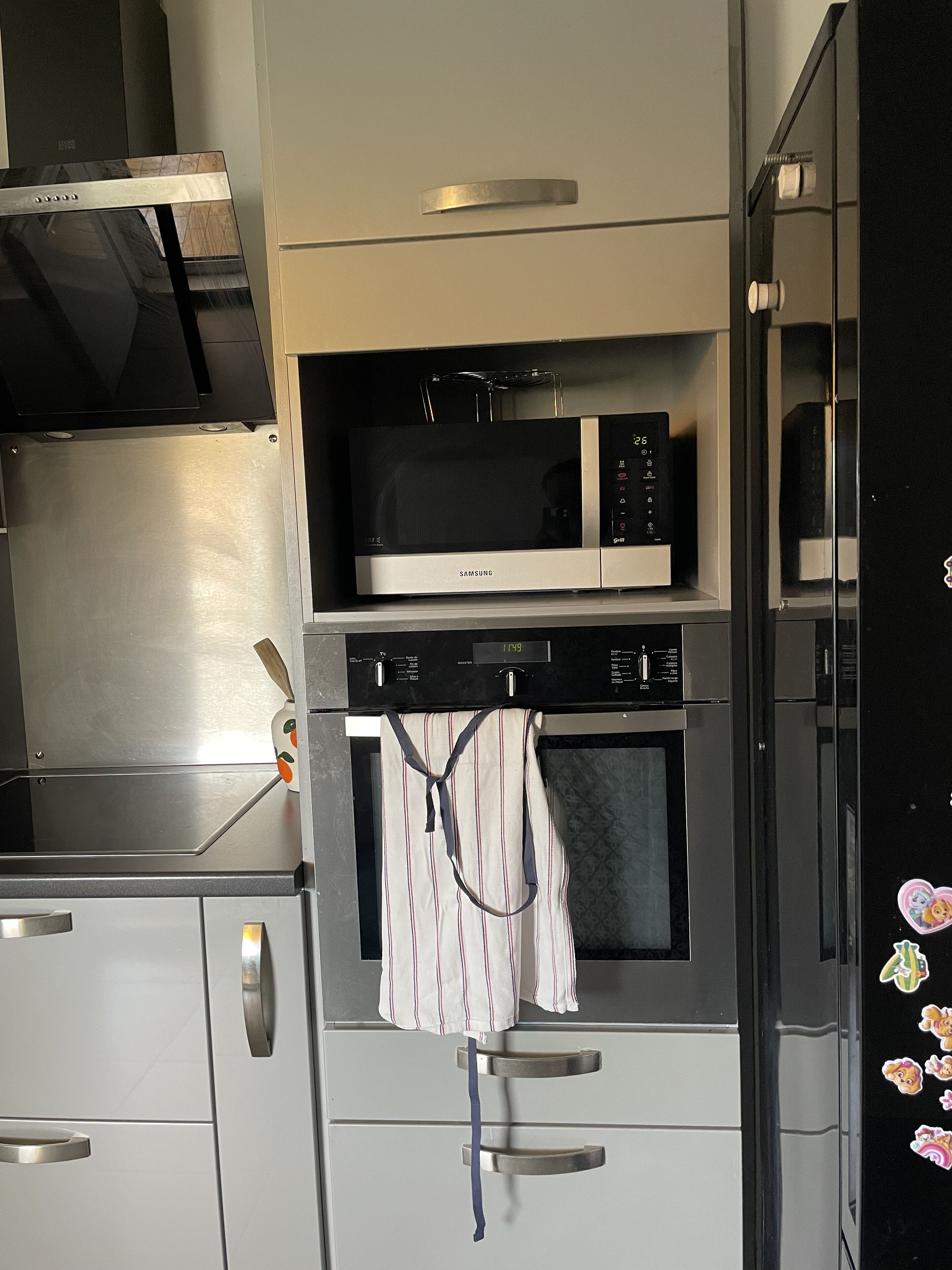 Een keuken met een magnetron, oven en keukenkastjes van roestvrij staal.