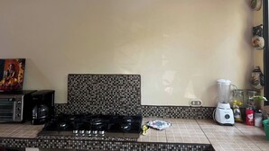 A kitchen with a gas stove, a coffee maker, a blender, and a toaster.