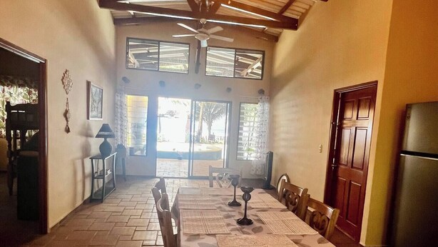 A dining area with a high ceiling, a ceiling fan, and a table set for dining.