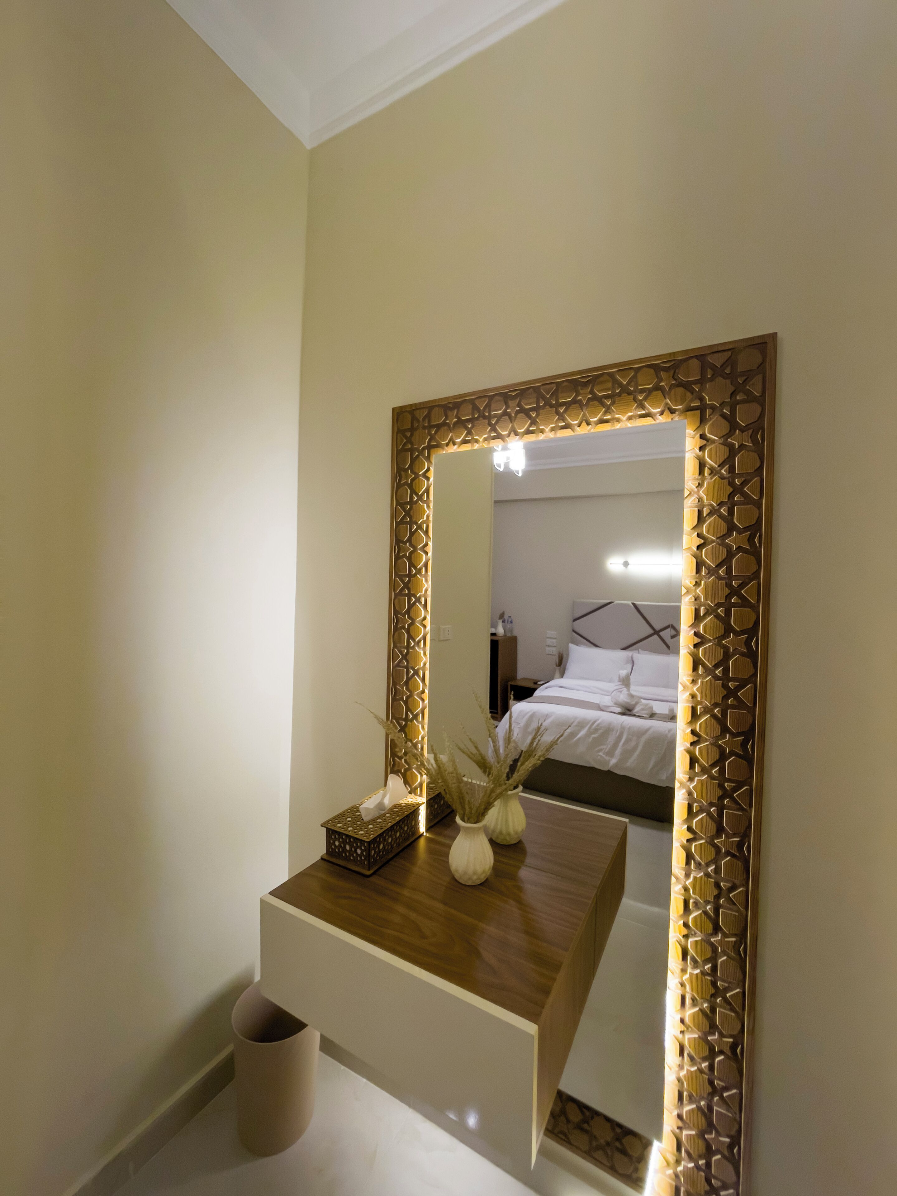 A bedroom with a bed, bedside table, and a mirror with a decorative frame.