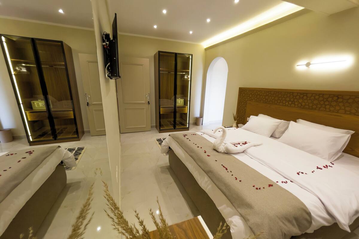 A hotel room with a large bed, a wardrobe, and a mirror.