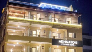 A multi-story hotel with a prominent sign for "AKHNATON Pyramids Hotel". - Akhnaton Pyramids View (Giza)