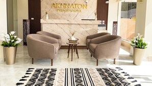 A reception area with a marble wall, two sofas, a small table, and potted plants. - Akhnaton Pyramids View (Giza)