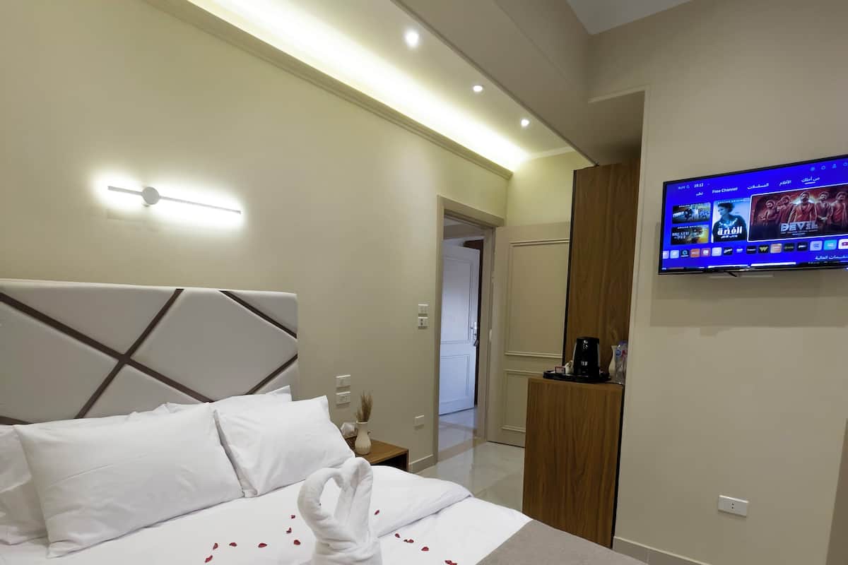 A hotel room with a large bed, a flat-screen TV mounted on the wall, and a modern design.