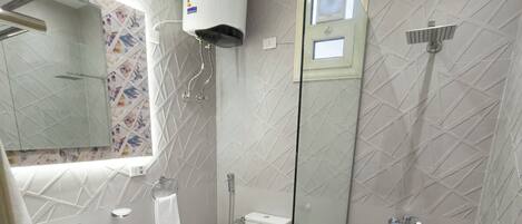 A modern bathroom with a glass-enclosed shower, a sink with a marble countertop, and a toilet.