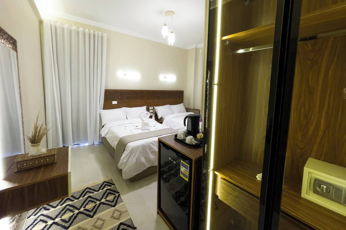 A hotel room with a bed, bedside table, and a minibar.