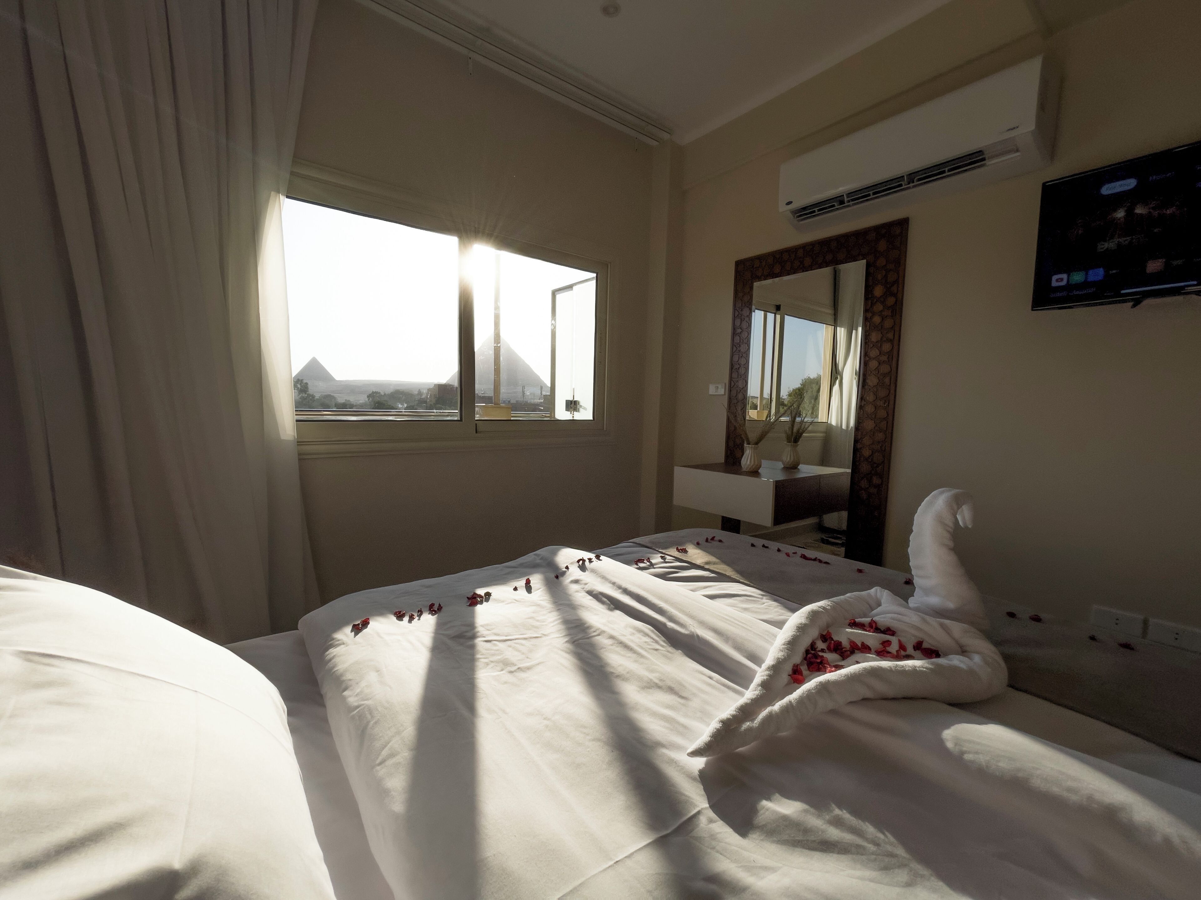 Quarto de hotel com cama, janela, espelho e ar condicionado.