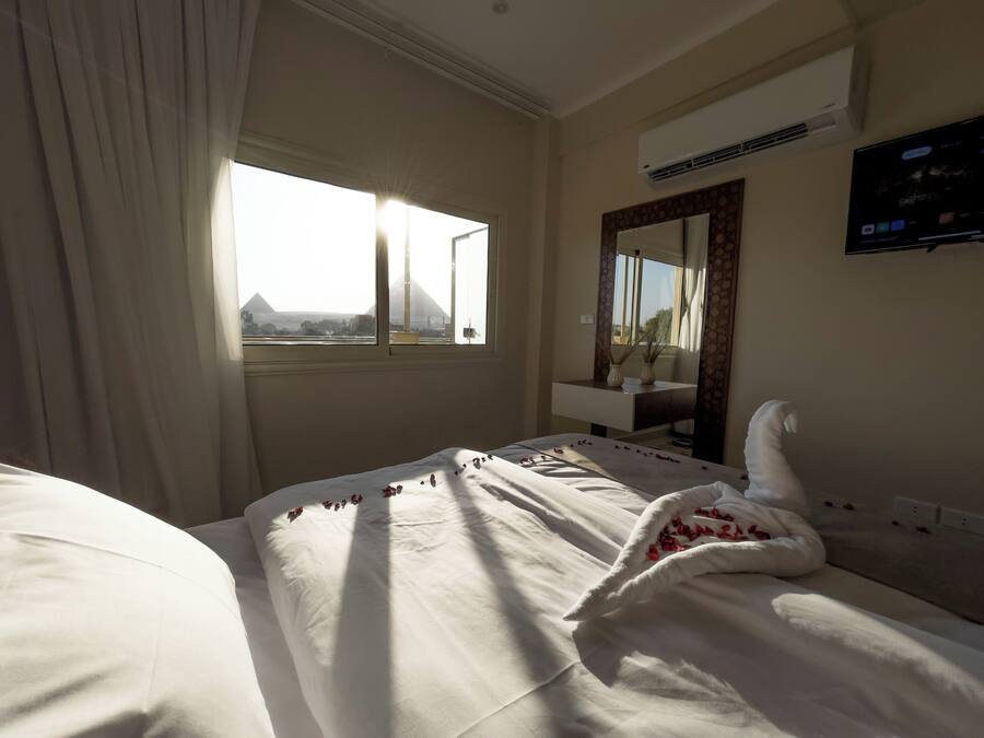Una habitación de hotel con cama, ventana, espejo y aire acondicionado.