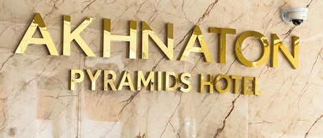 A marble wall with the text "AKHNATON PYRAMIDS HOTEL" in gold letters.