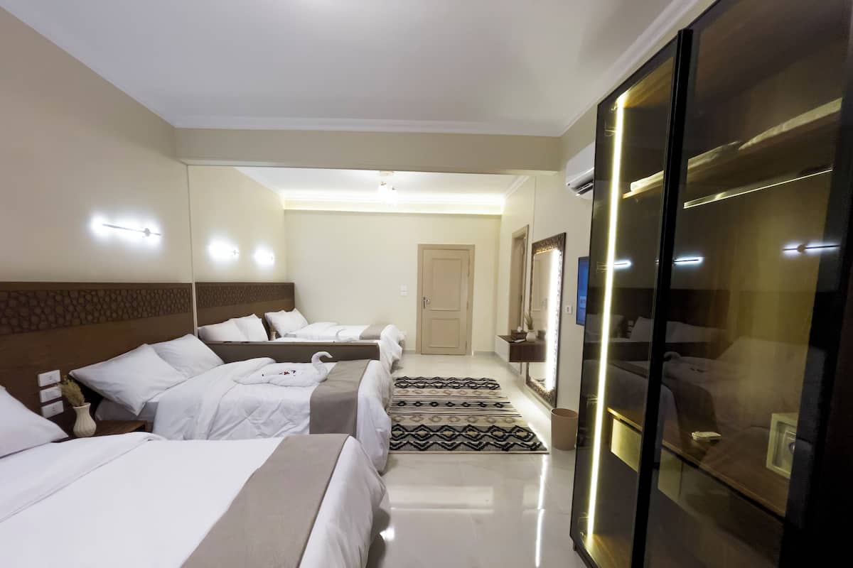 A hotel room with three beds, a large mirror, and a glass partition.