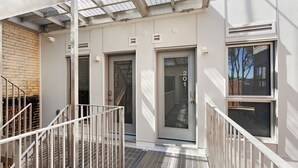 Un edificio moderno con una escalera de metal, una puerta de cristal con el número 201 y una barandilla metálica.