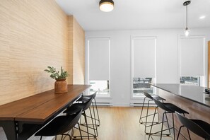 Un espace repas moderne avec une table en bois, des chaises noires et une plante en pot.