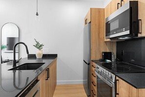 Una cocina moderna con encimera negra, electrodomésticos de acero inoxidable y armarios de madera.