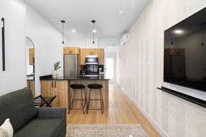 Una cocina moderna con armarios de madera, encimera negra y dos taburetes de bar.