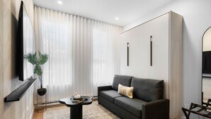 Una sala de estar moderna con un sofá, una mesa de centro, una planta y un televisor montado en la pared.