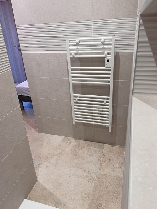 A bathroom with a white towel rack, tiled walls, and a shower area.