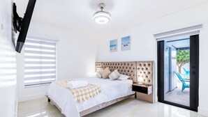 A bedroom with a bed, a nightstand, a TV mounted on the wall, and a sliding glass door leading to an outdoor area. - Escape to Miami/Heather+Pool/9pl/BBQ/pool table. (Miami)