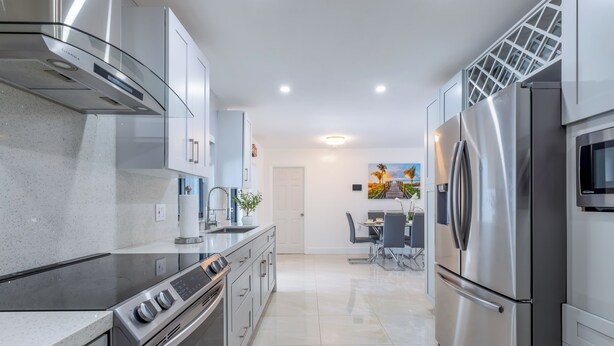 A modern kitchen with stainless steel appliances, a central island, and a dining area with a view. - Escape to Miami/Heather+Pool/9pl/BBQ/pool table. (Miami)