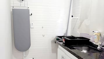 A bathroom with white tiled walls, a marble floor, a grey toilet, a black sink, and a white cabinet with drawers.