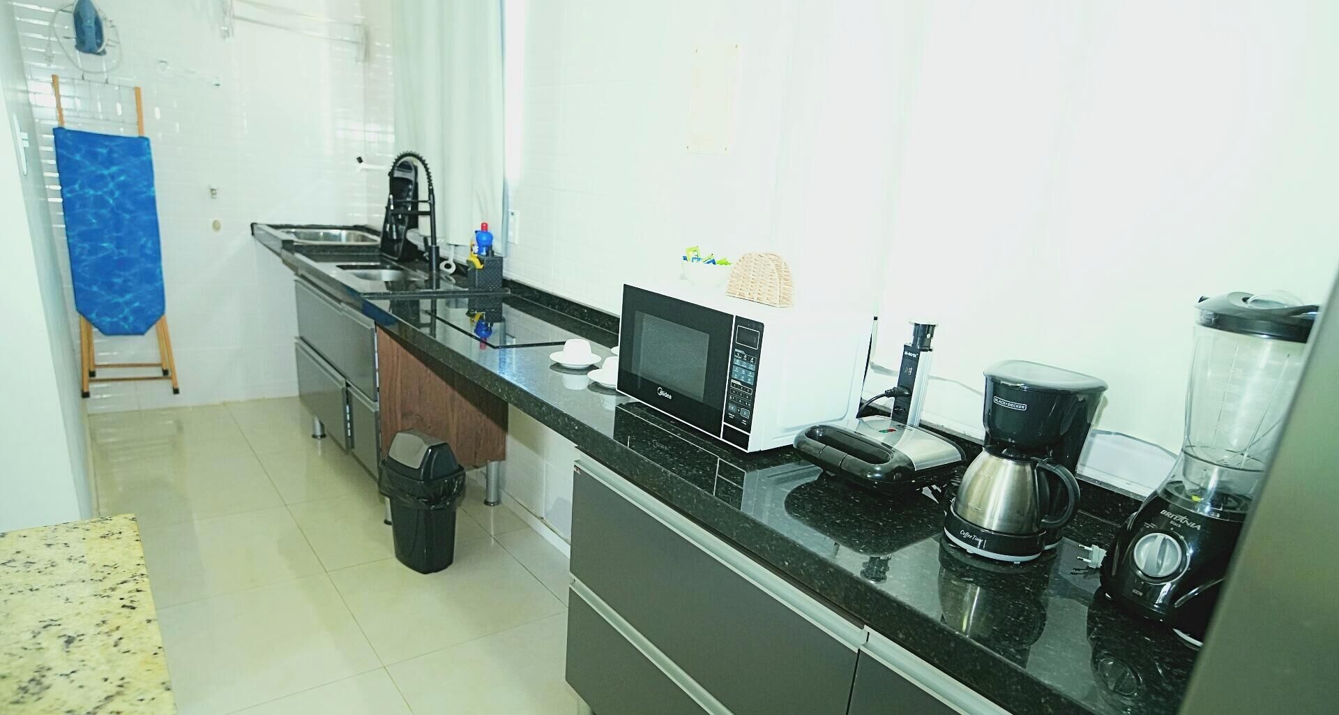 Una cocina con microondas, cafetera y licuadora sobre la encimera.