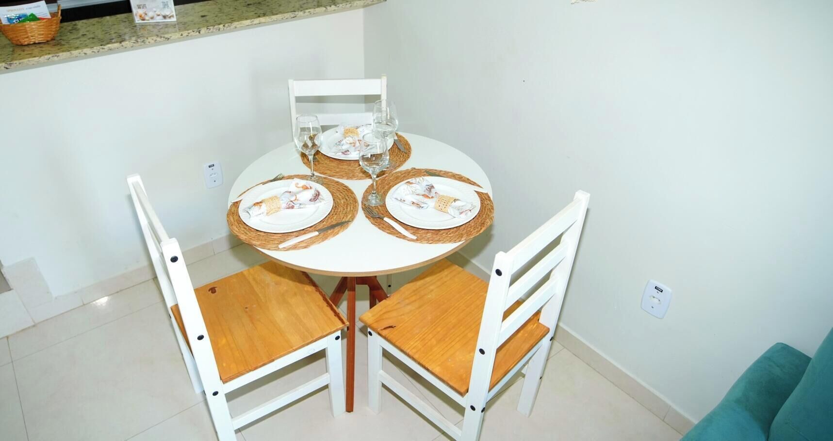 Un pequeño comedor con una mesa redonda, dos sillas y una cesta en la encimera.