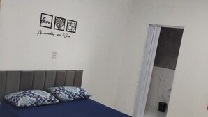Un dormitorio con una cama, una pared adornada con tres cuadros enmarcados y una puerta que da a un baño.