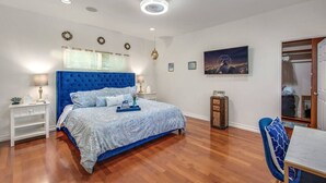 Un dormitorio con una cama grande, una mesita de noche, un aparador, una silla y un cuadro en la pared.