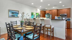 Una cocina moderna con armarios de madera, una isla central y un comedor con una mesa dispuesta para seis comensales.