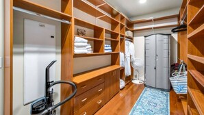 Un vestidor con estantes de madera, una puerta blanca y un armario gris.