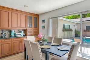 A modern kitchen with wooden cabinets and a dining area with a table set for four.