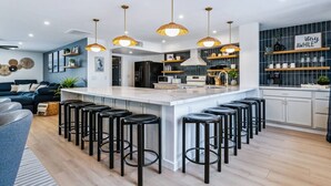 Une cuisine moderne dotée d’un îlot central, de tabourets de bar, de luminaires suspendus et d’un bar intégré à l’îlot de cuisine.