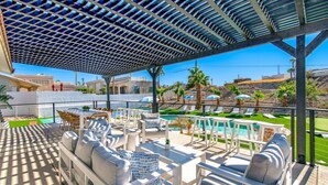 Une terrasse extérieure avec des meubles blancs, une piscine et une vue sur le paysage environnant.
