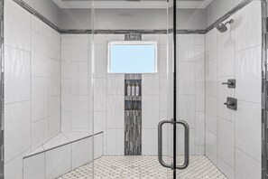 A modern shower with a glass door, a tiled floor, and a small shelf with toiletries. - Private Beach Access, Dog-Friendly, Free Cancellation (Bolivar Peninsula)