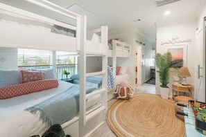 A bunk bed room with a view of the outside. There is a small table with a lamp and a plant.