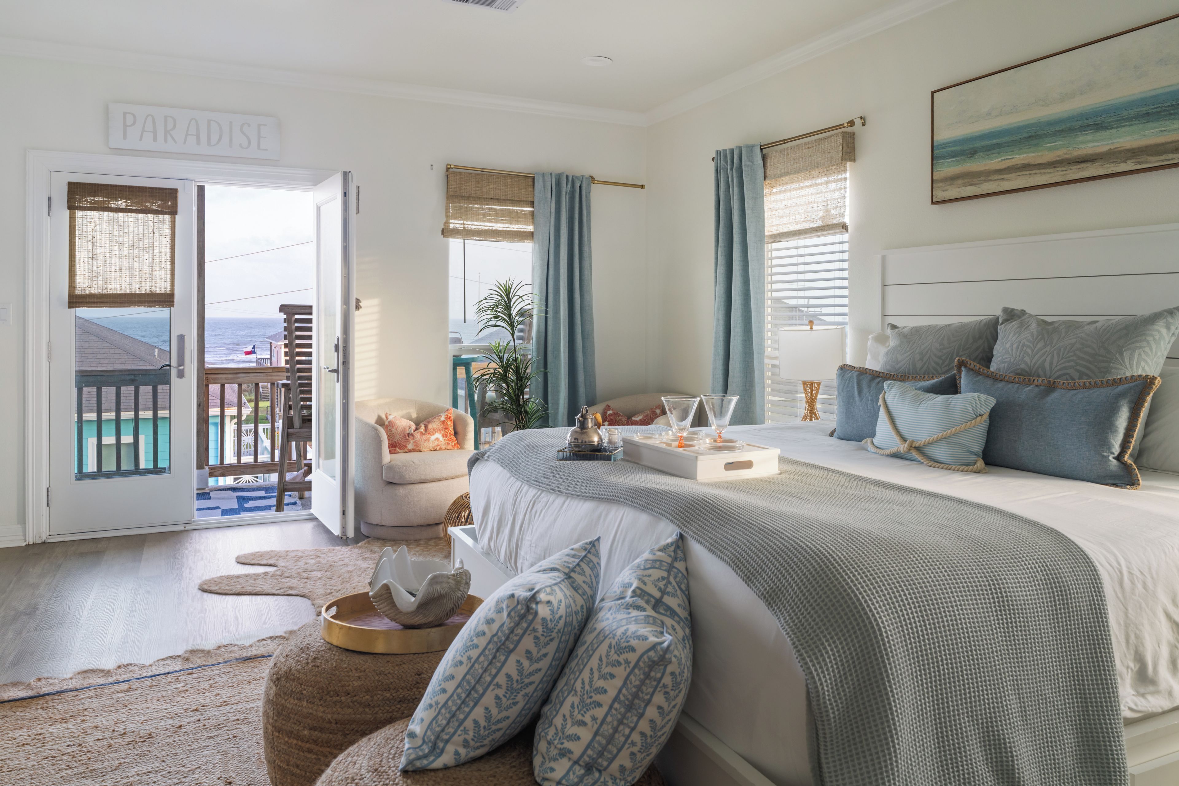 A bedroom with a bed, a nightstand, a window with curtains, a view of the outdoors, and a sign on the door.