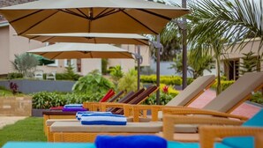 A poolside area with lounge chairs and umbrellas. - INOGA LODGE KARATU (Karatu)