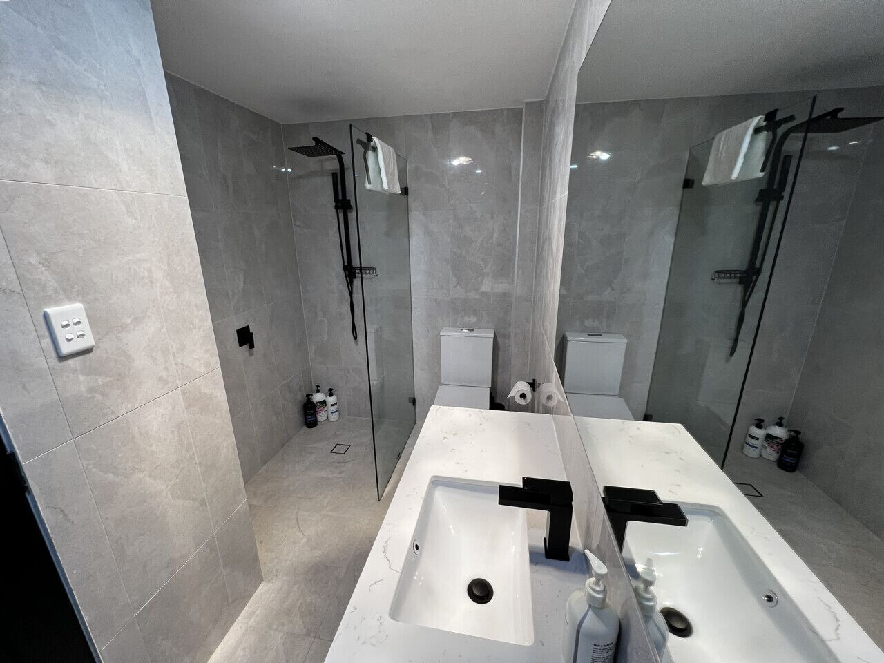 Une salle de bain moderne avec un grand lavabo blanc, une douche à parois de verre et des toilettes.