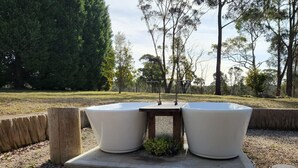 Two large white planters on a concrete platform surrounded by gravel, with trees in the background.
