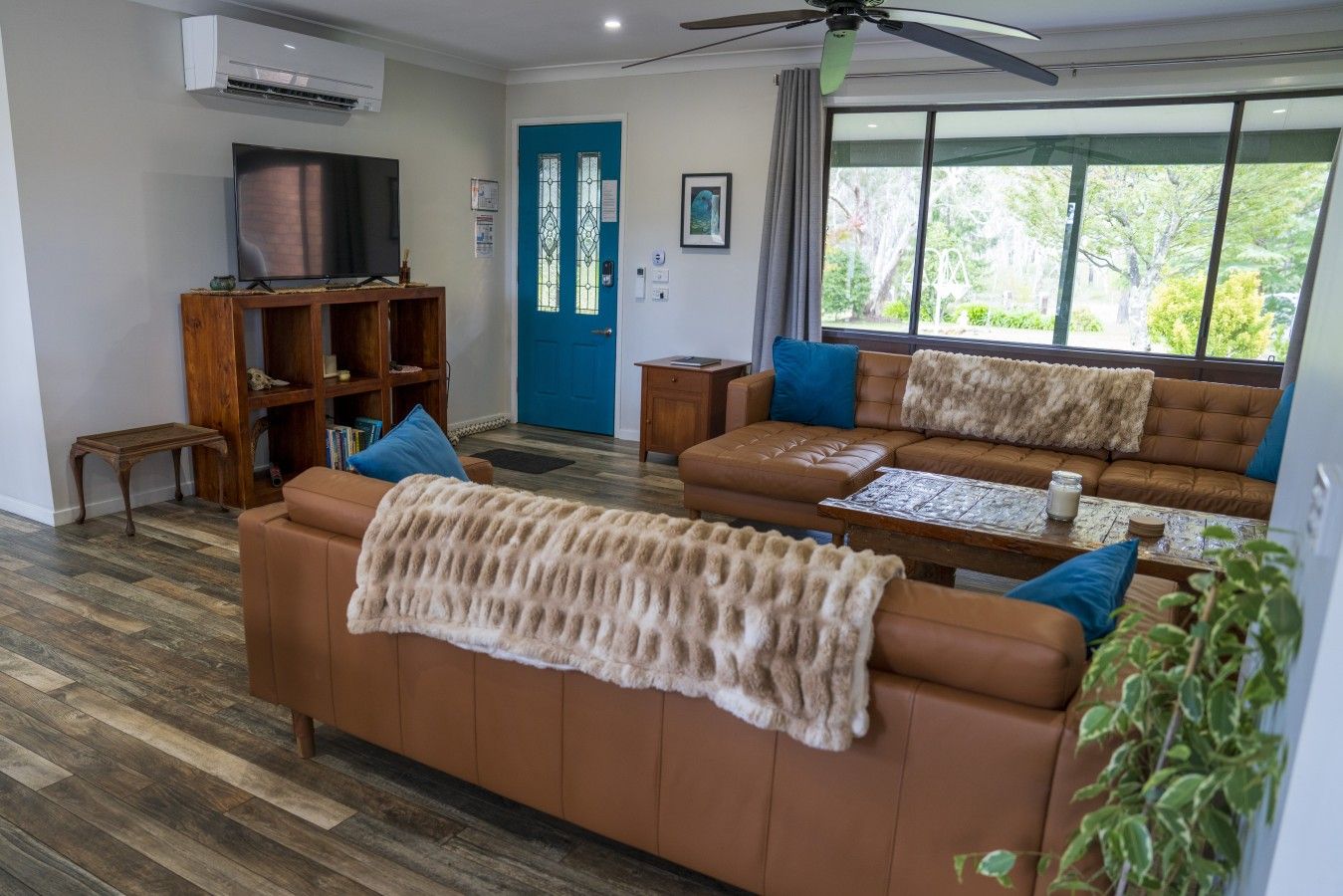 A living room with a brown sofa, a coffee table, and a television on a wooden stand.