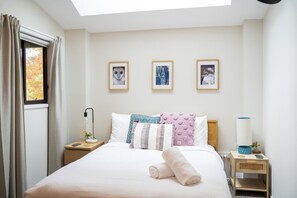 A hotel room with a bed, a bedside lamp, a nightstand, a window with curtains, and three framed pictures on the wall. - Fettlers Lodge - zigzag railway, peaceful, acreage, pet friendly (Clarence)