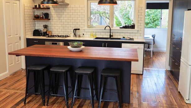 A modern kitchen with a central island, bar stools, pendant lighting, and a view of the outdoors. - BlackheathCottage|Cosy Woodfire|Quiet|Walks (Blackheath)