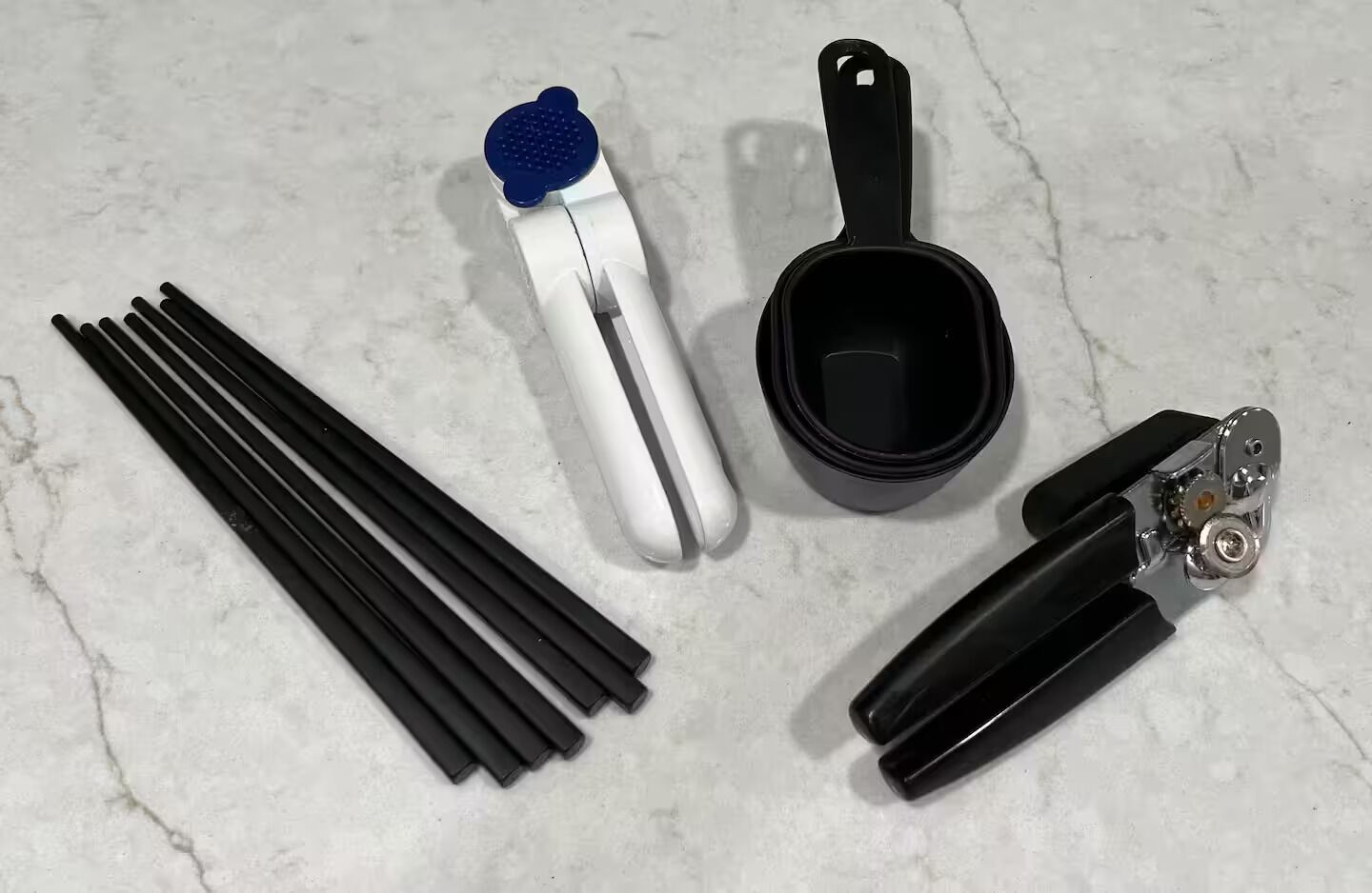 A set of kitchen utensils including a spatula, a ladle, a whisk, and a pair of tongs.