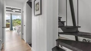 Et moderne interiør med en trappe, en dør der fører til en balkon, og et billede i ramme på væggen.