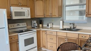 Una cocina con armarios de madera, microondas, horno, tostadora y pileta.