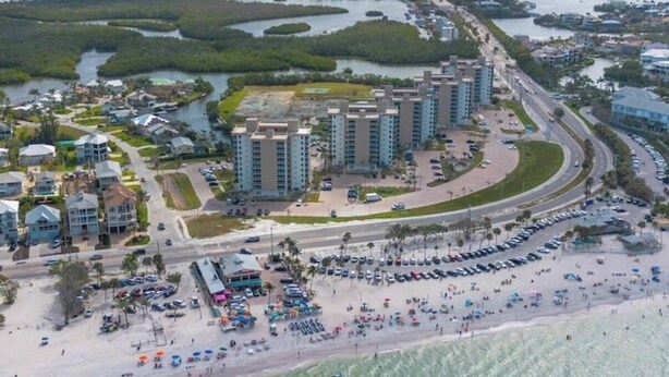 Un complejo turístico costero con rascacielos, un puerto deportivo y una playa con sombrillas.